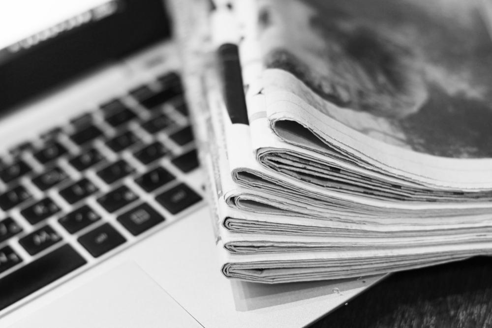 Newspaper sitting on Macbook in black and white